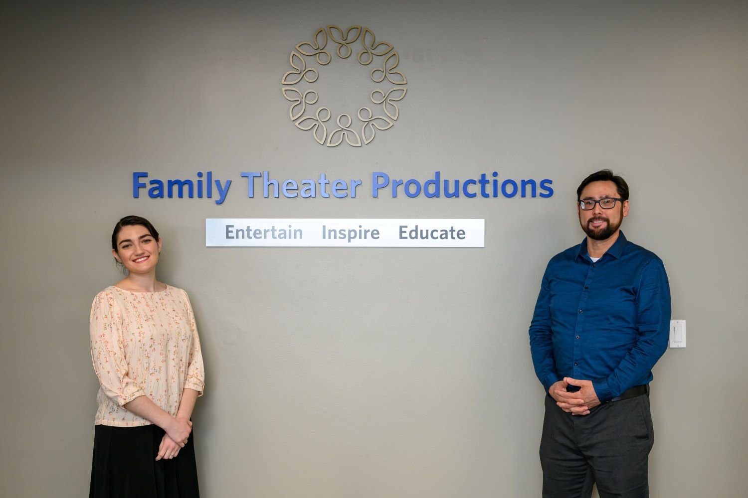 Two individuals stand in front of a 
