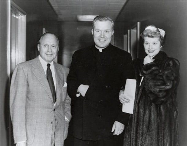 Three people posing in a hallway; one is dressed as a priest. Pictured are: Peyton and Lucille Ball and Jack Benny